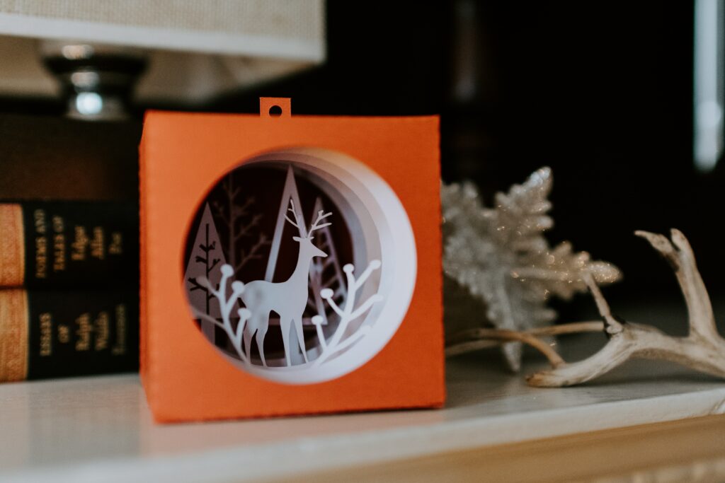 orange cutout Christmas ornament of a deer sits on a shelf
